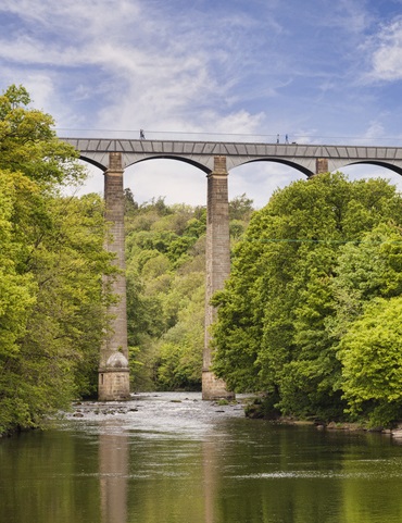 Pontcysyllte Aqueduct, built by Thomas Telford, and a World Heritage Site, reflecting in the River Dee, with incidental people walking across, near Llangollen, County Borough of Wrexham, Wales, UK